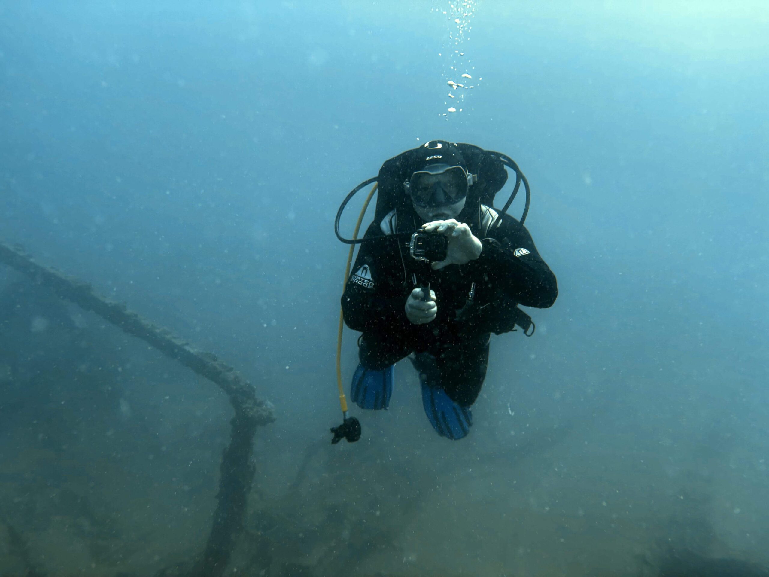 Taucher mit korrekt befestiger GoPro Hand Halterung unterwasser über Schiffswrack