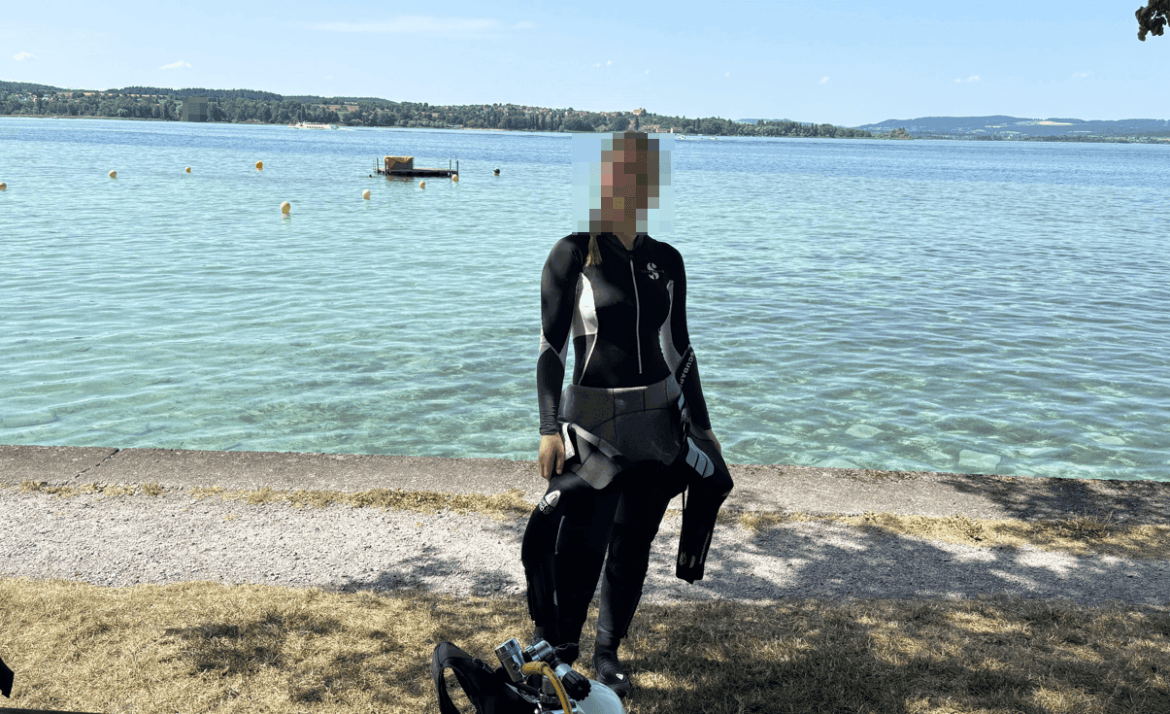 Junge Taucherin zieht ihren Tauchanzug am See mit Leichtigkeit an