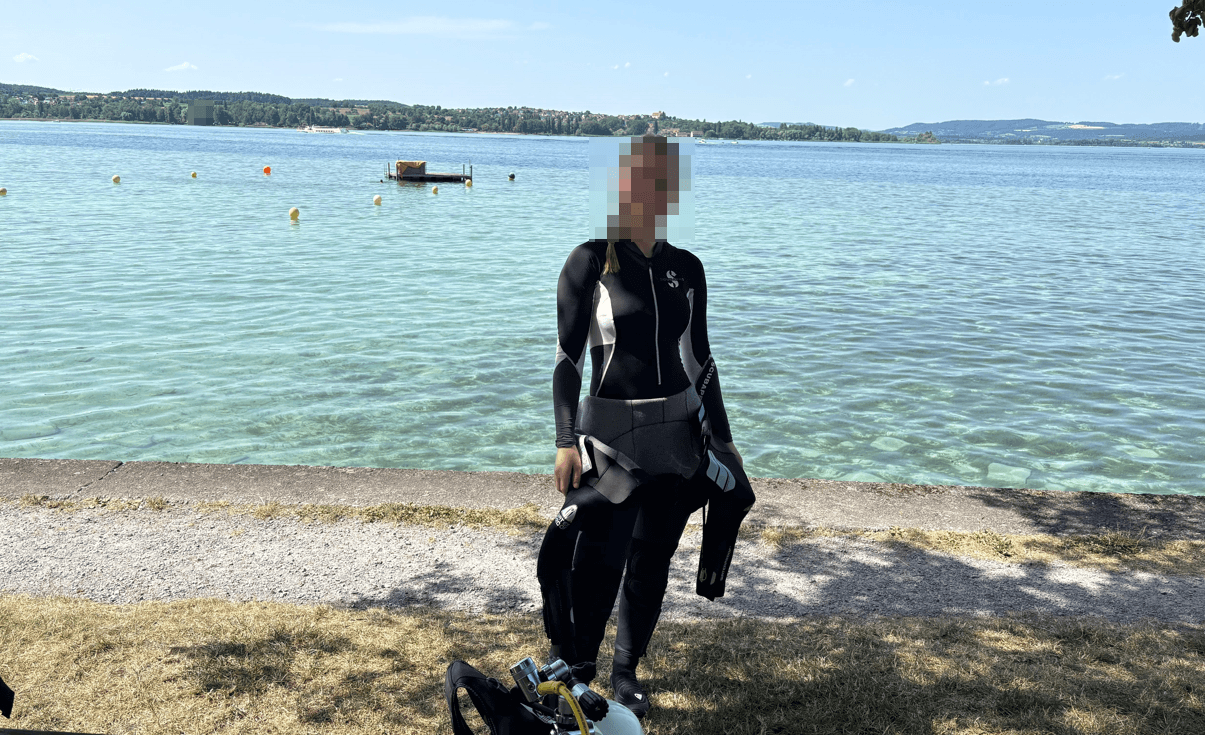 Junge Taucherin zieht ihren Tauchanzug am See mit Leichtigkeit an