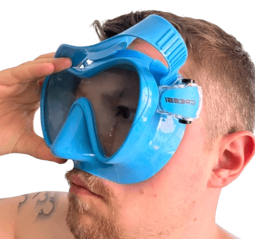 Taucher prüft den Sitz einer blauen Cressi-Tauchmaske an einem schmalen Gesicht.