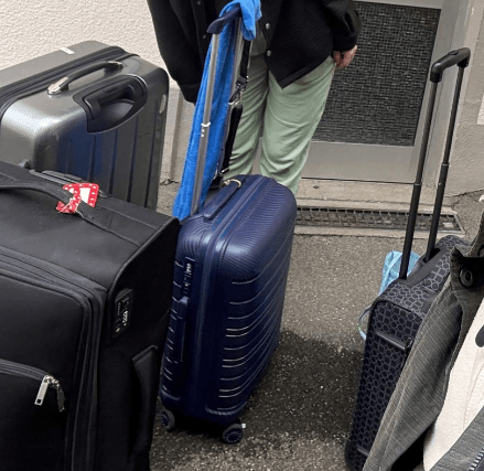 Ein schwarzer großer Stoffkoffer, grauer Hartschaltenkoffe und zwei Handgepäckskoffer mit Tauchgepäck stehen vor der Haustür.